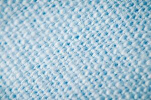 Makroaufnahme einer hellblauen, flauschigen Textiloberfläche mit sichtbaren Faserknötchen