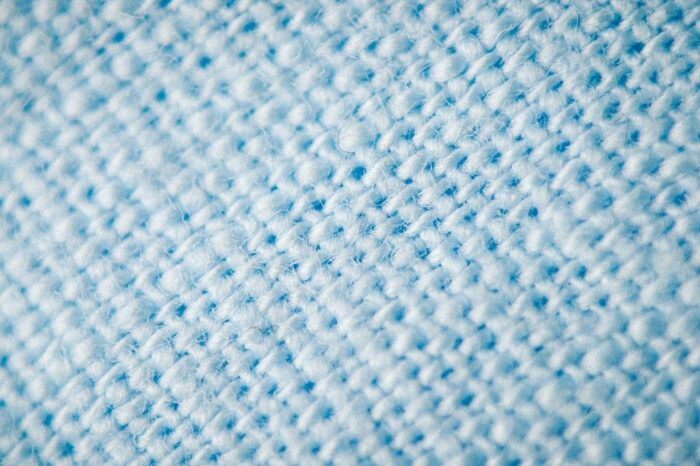 Makroaufnahme einer hellblauen, flauschigen Textiloberfläche mit sichtbaren Faserknötchen